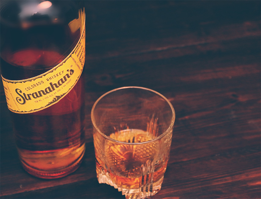 Stranahan\'s whiskey bottle next to glass