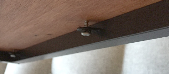 Screw holding table top on