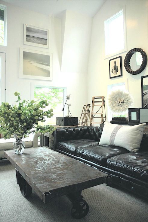 A living room filled with black leather couch and a large window