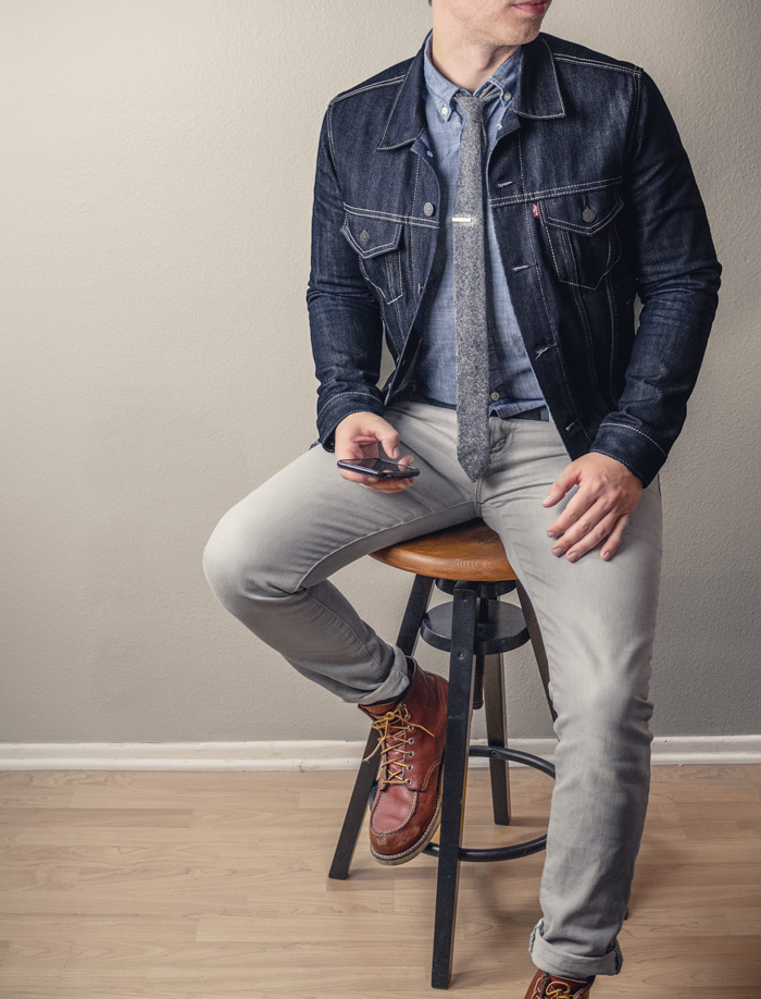 man wearing casual outfit with chambray shirt, denim jacket gray jeans, knit tie, and red wing boots