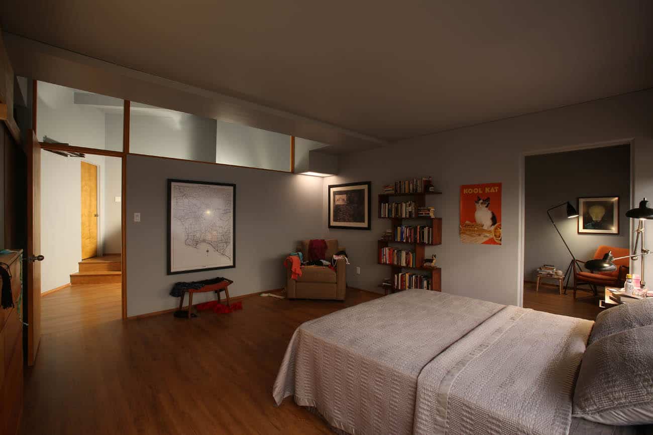 A bedroom with a bed and chair and art