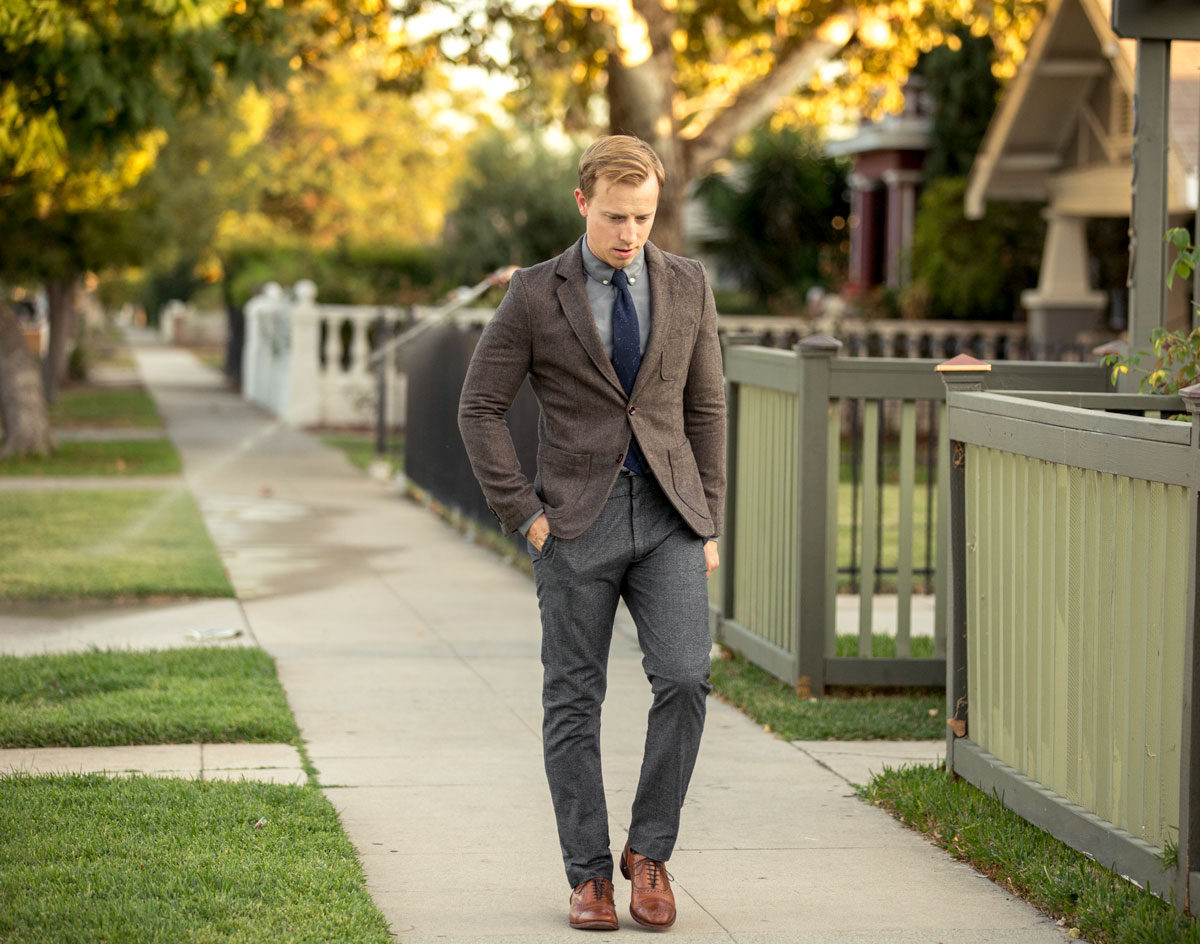 A man wearing a suit and tie walking on a sidewalk