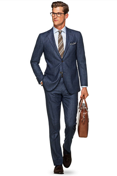 A man wearing a herringbone suit and tie