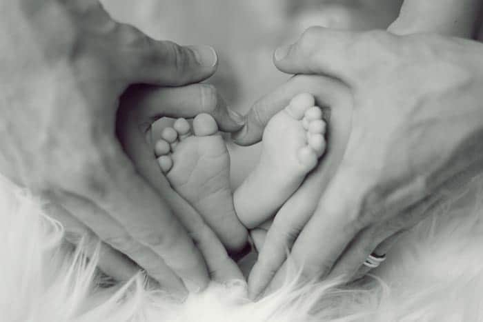 Baby feet and parent hands forming a heart