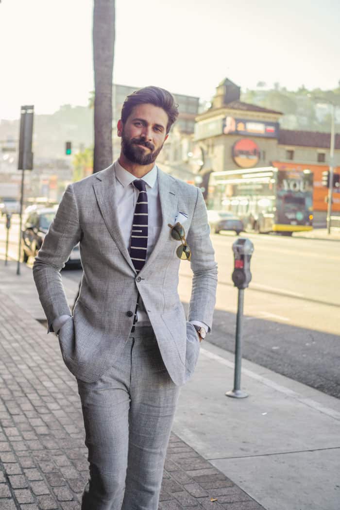 A man walking while wearing a gray suit