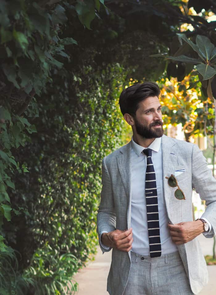 A man wearing a suit buttoning his jacket