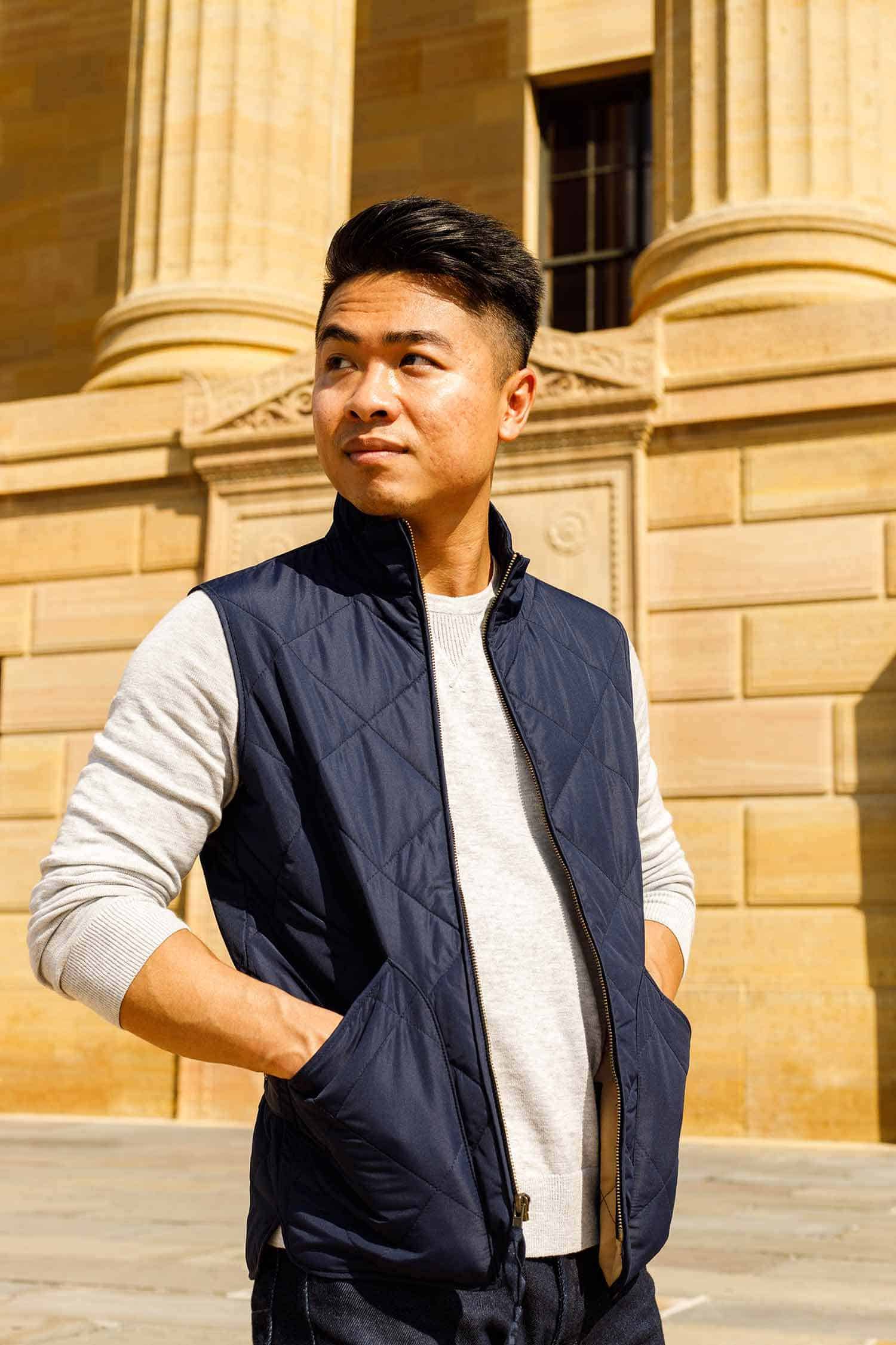 A man standing in front of a building wearing a vest