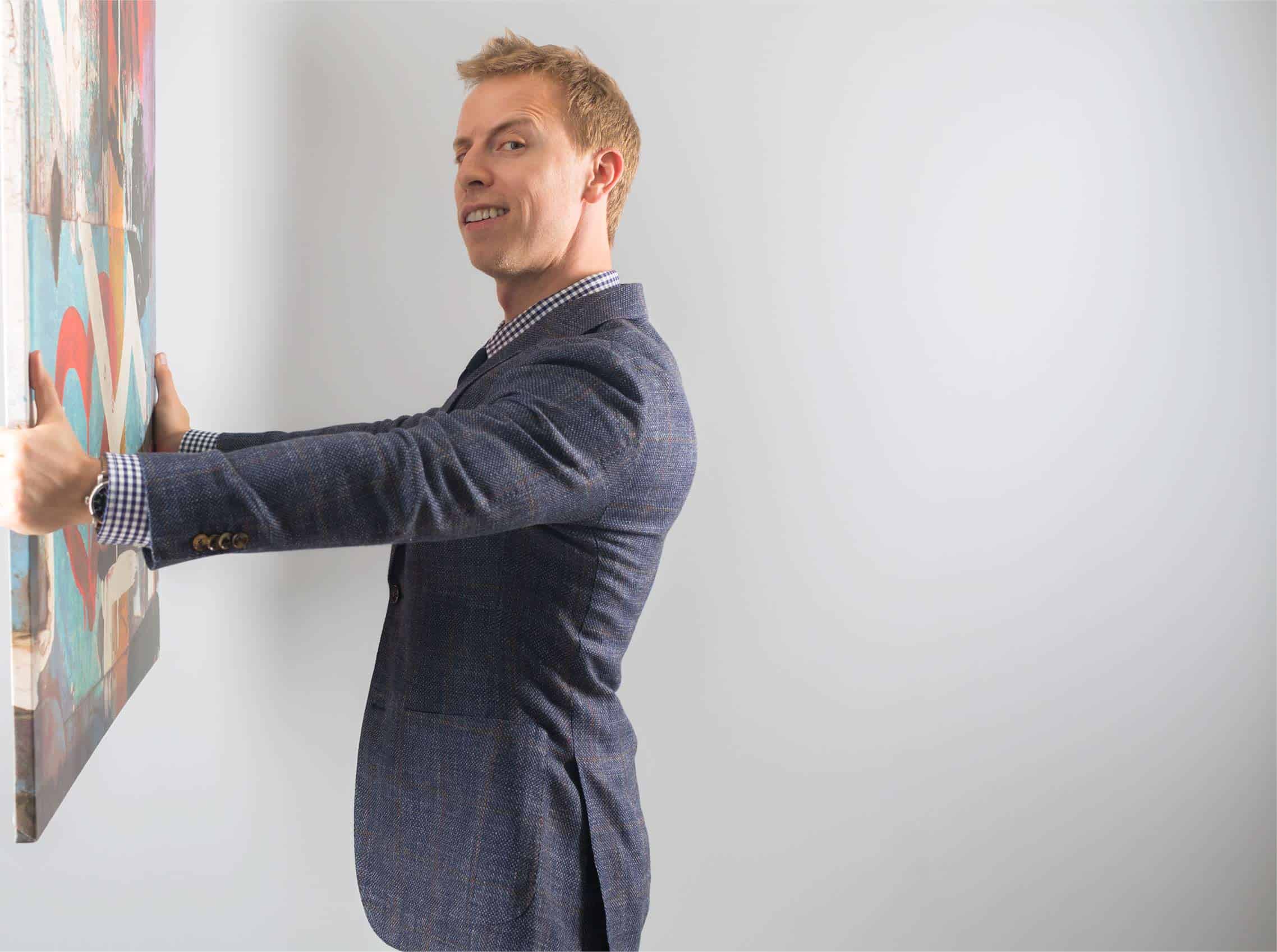 A man in a suit holding a painting