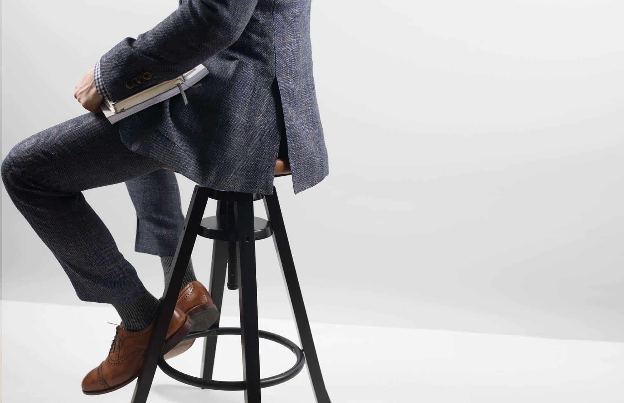 A person wearing a suit sitting on a stool