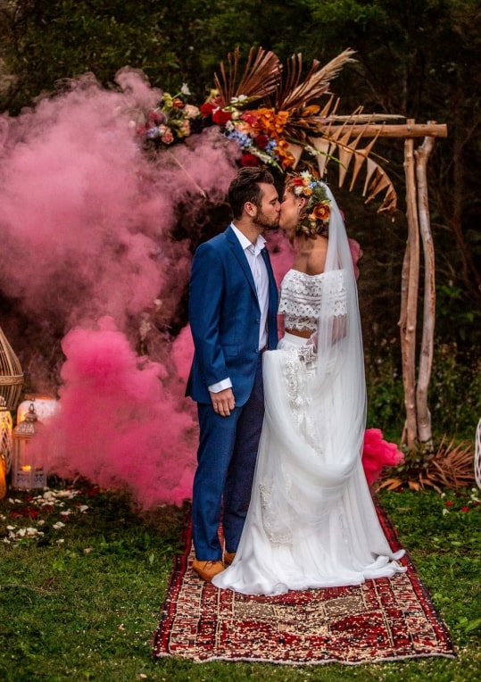 A groom and bride kissing with pink smoke