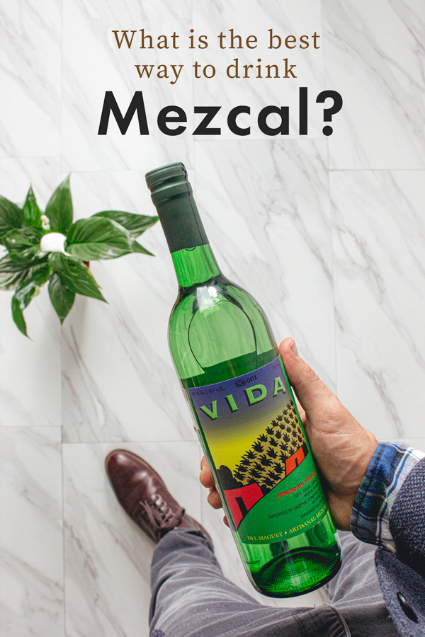 A person holding a bottle of mezcal