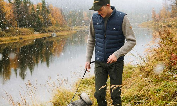 man wearing fjallraven vest walking next to water