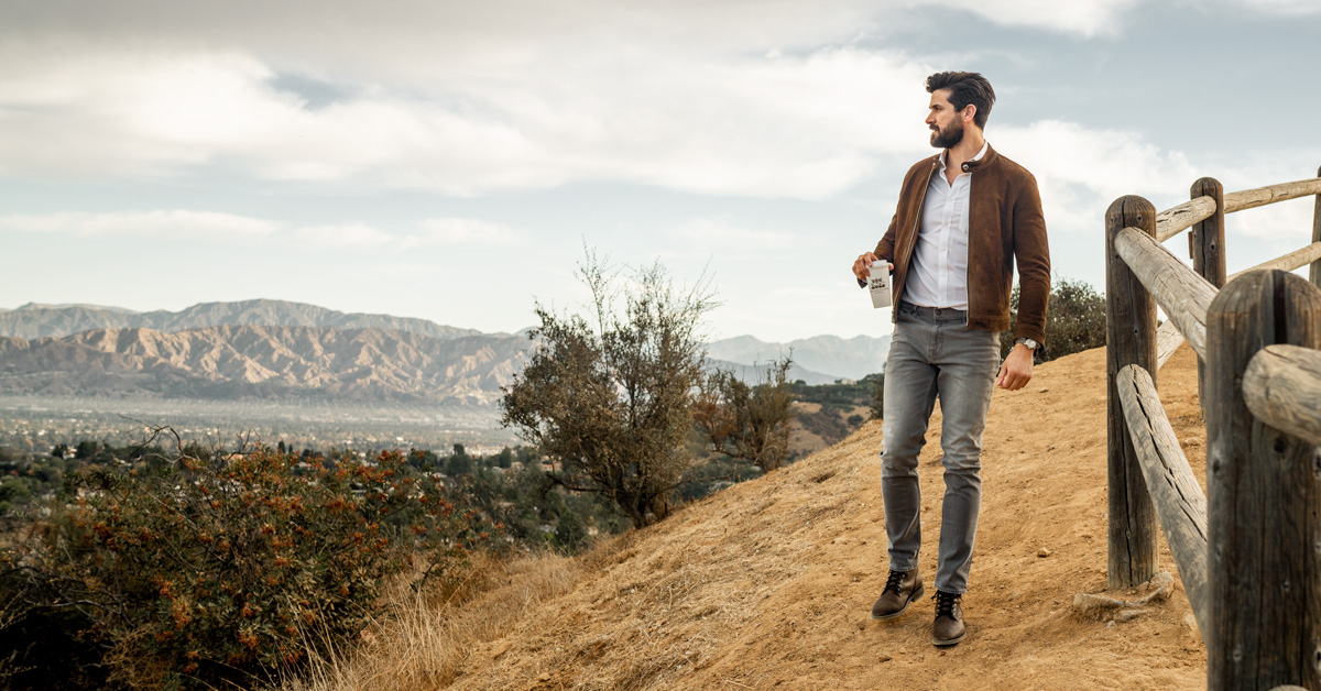 man wearing leather racer jacket in front of landscape