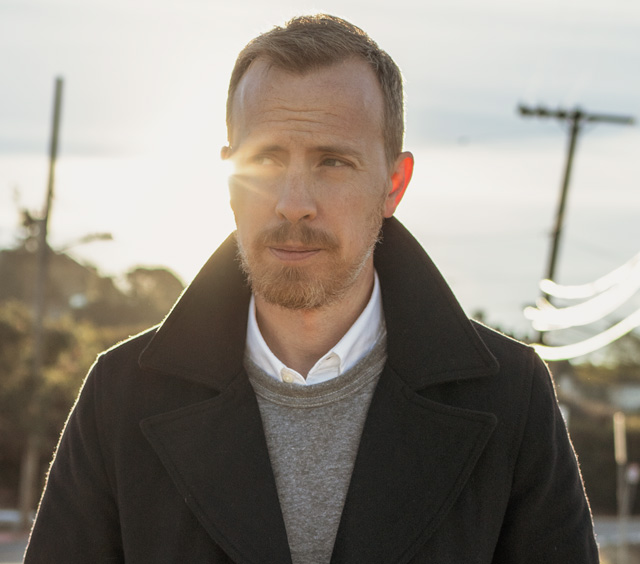 Close up of man wearing a white oxford shirt under sweatshirt and pea coat