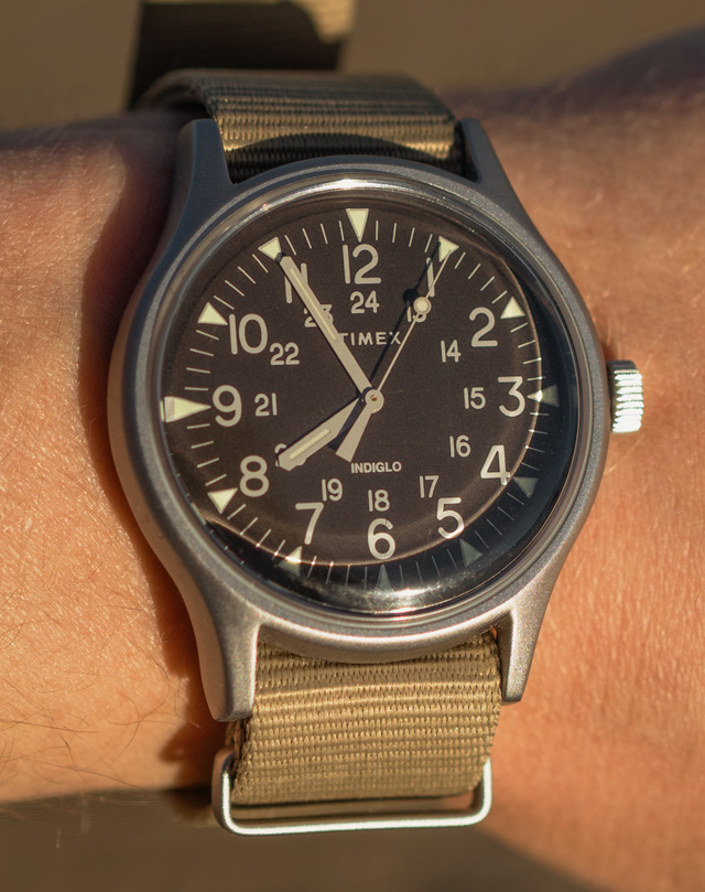 Timex watch with a black face and tan cloth NATO strap