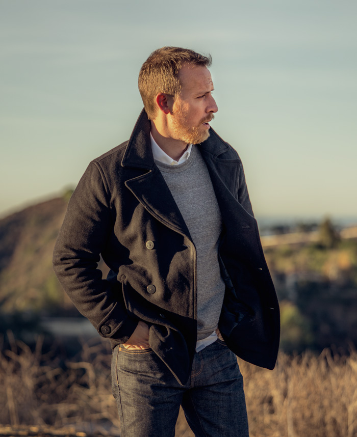 black pea coat with gray sweatshirt and white button shirt