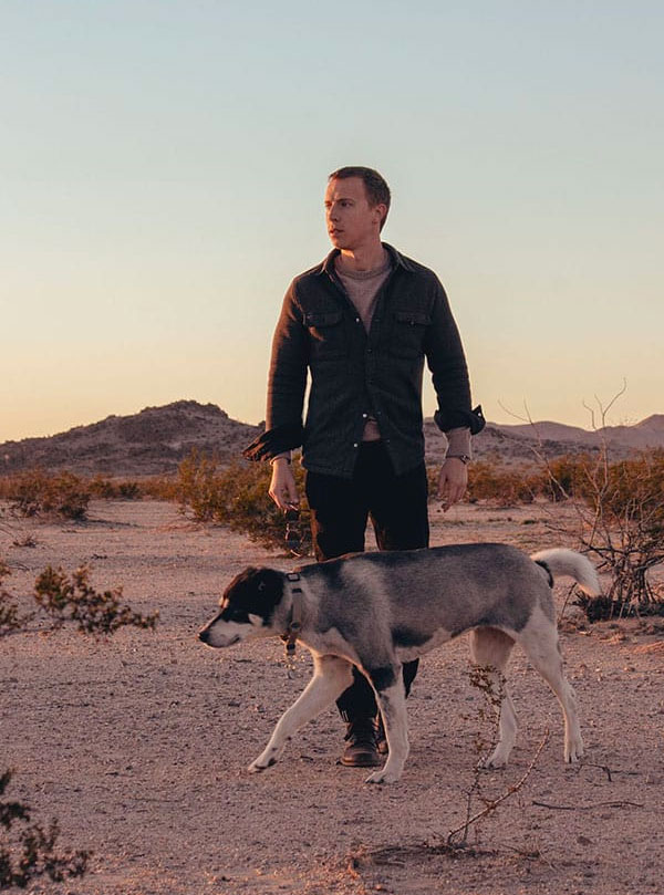 shirt jacket outfit with cashmere sweater and black jeans - man and dog in desert