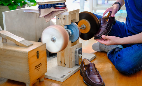 person using a shoe polisher machine to polish penny loafer shoes
