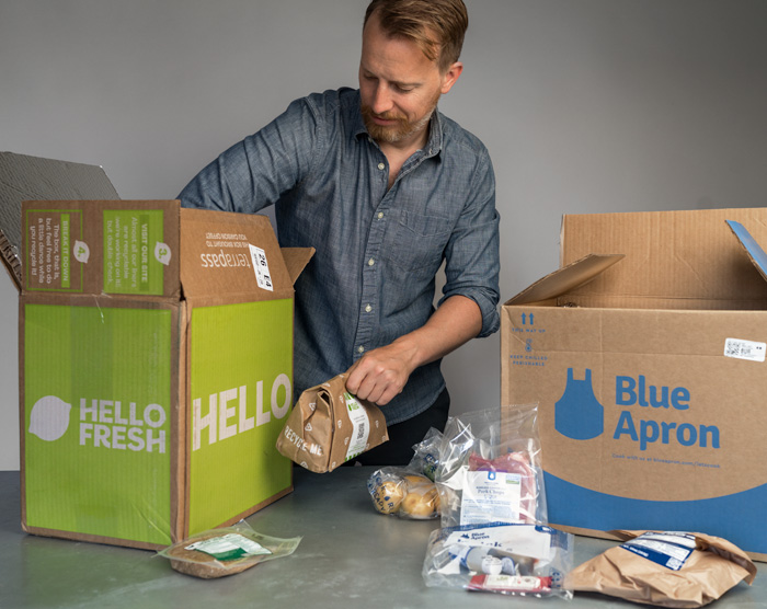 man taking items out of hello fresh and blue apron subscription boxes