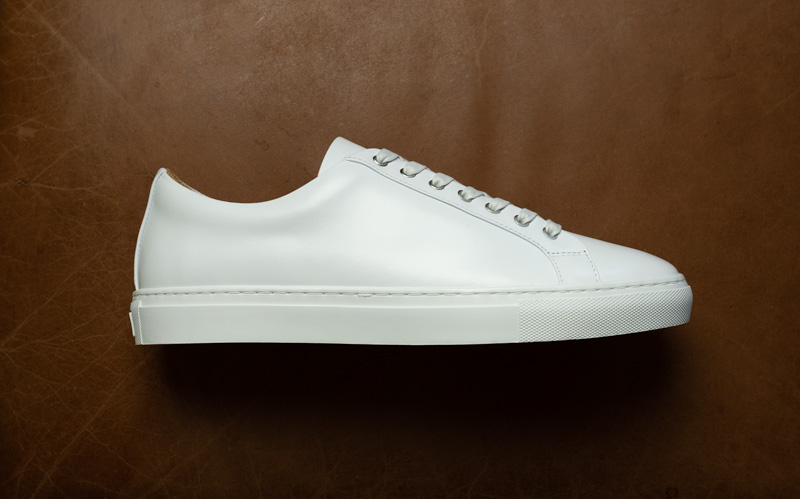 white leather sneakers on brown leather background