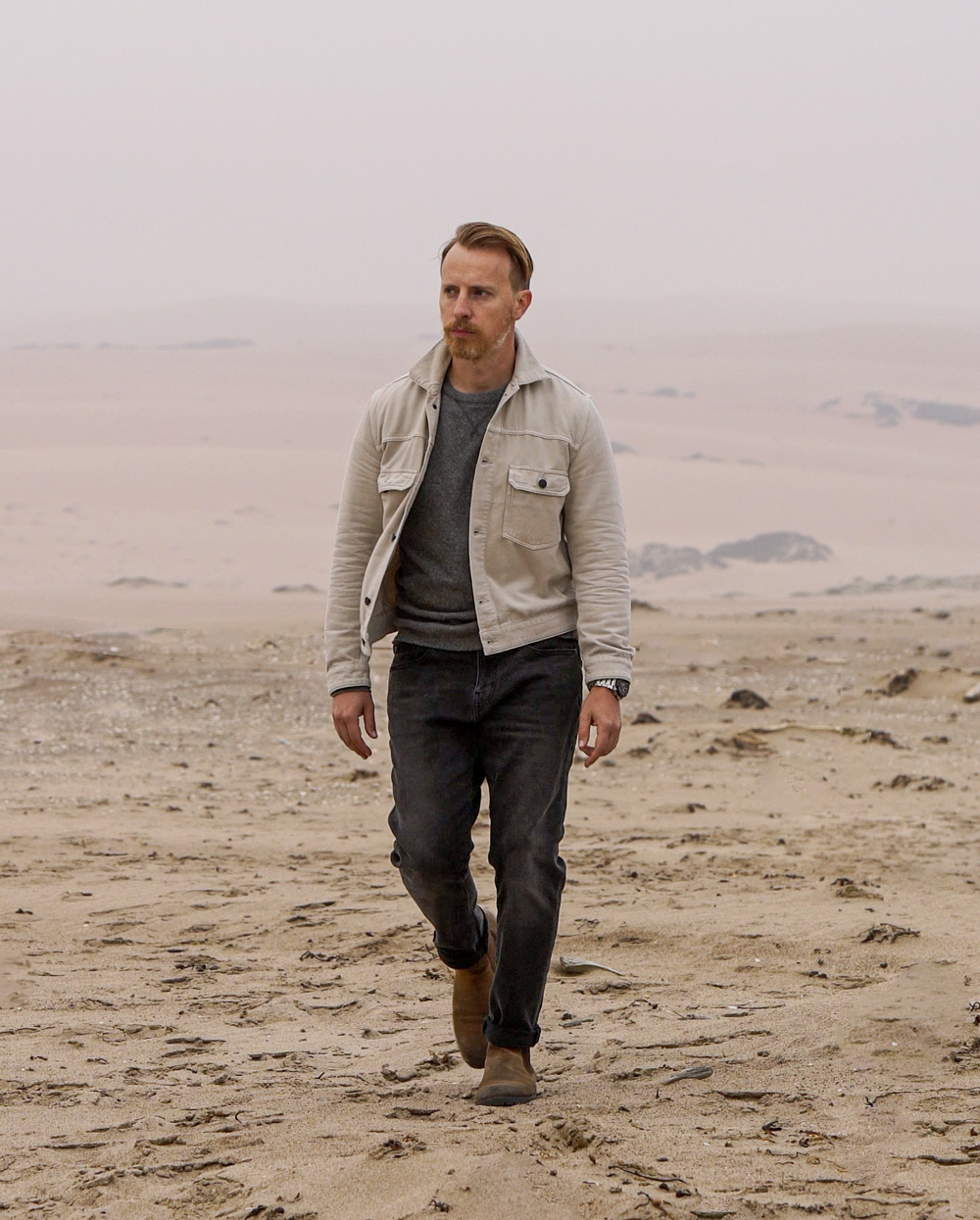 man in desert wearing Buck Mason trucker jacket, J.Crew gray sweatshirt, Goodthreads jeans, Thursday boots