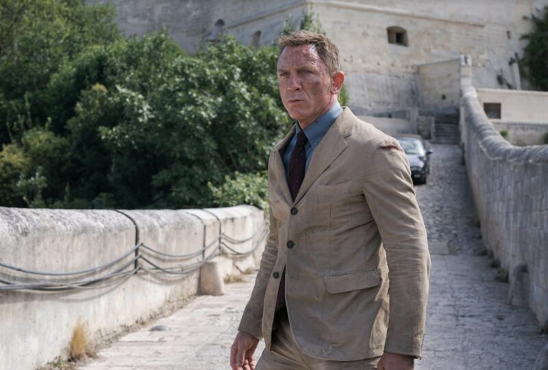 daniel craig james bond wearing a tan suit and blue shirt