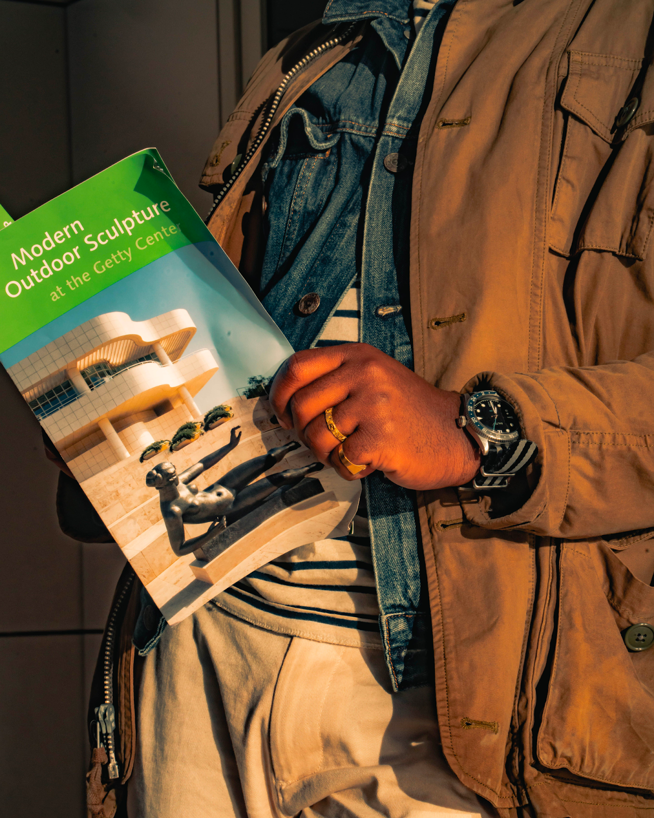 a man wearing a layered outfit with a field jacket, a denim jacket, and a shirt