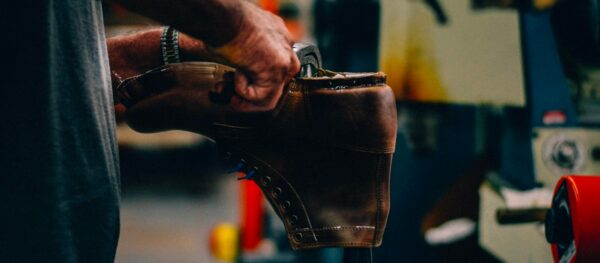 image of a brown leather boot held by the sole