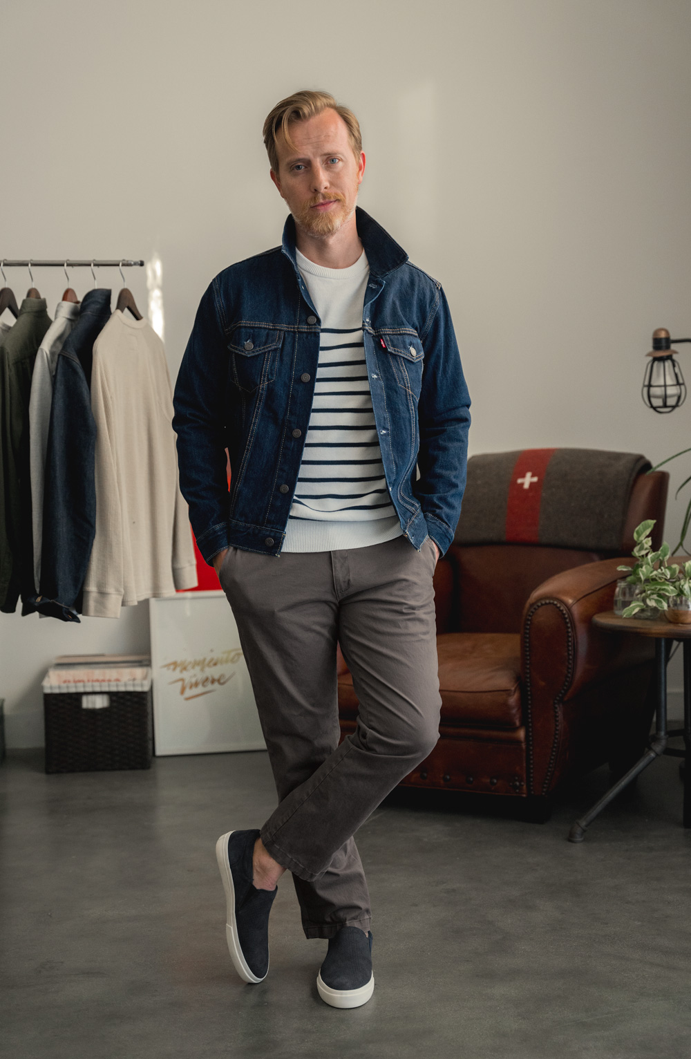 men's casual outfit idea with Levis trucker jacket, striped sweater, beige chinos, and black suede slip on sneakers