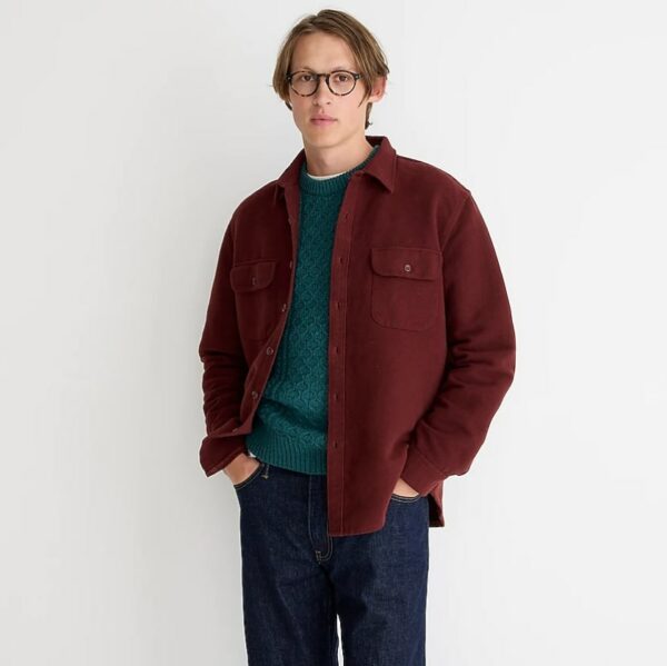 a man wearing a dark red chamois workshirt over a green shirt and blue denim jeans