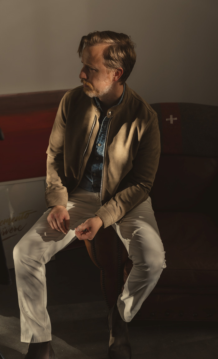 men's outfit with taupe suede jacket, blue chambray shirt, khaki pants, and olive suede chelsea boots