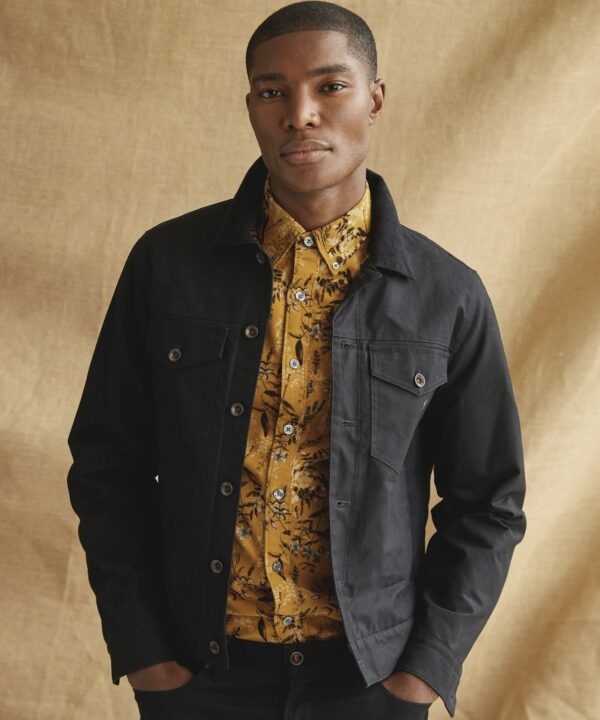 a man wearing a waxed jacket over a printed button front shirt