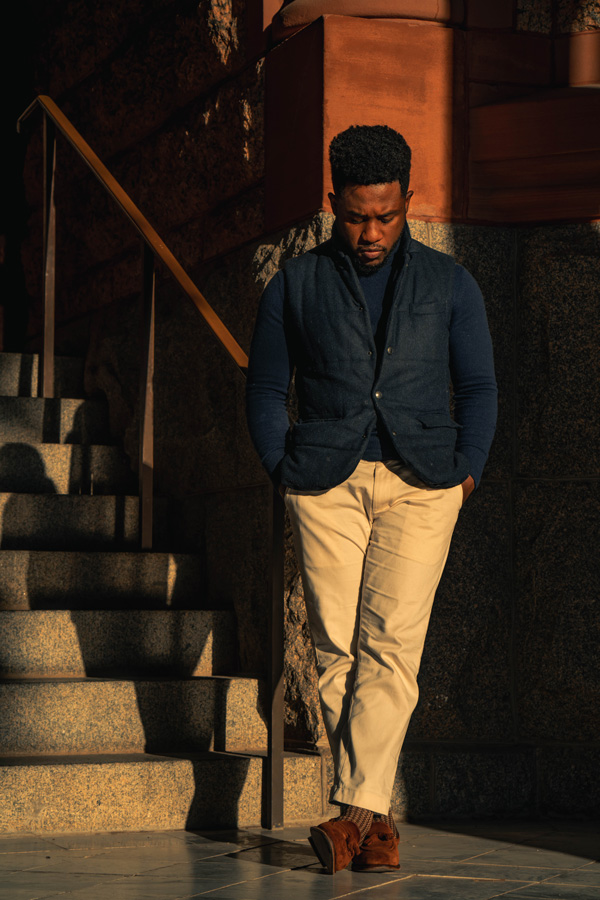 a man wearing a navy blazer and a turtleneck shirt and khaki pants