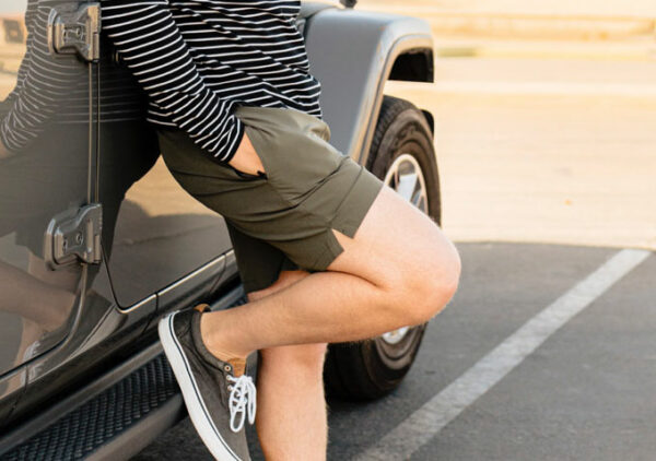 a person wearing green swim trunks and a striped long sleeve shirt