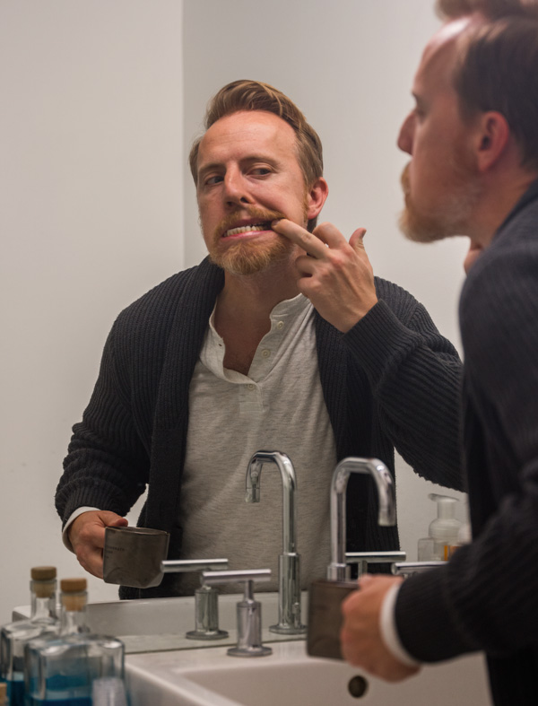 man looking at his teeth in the mirror