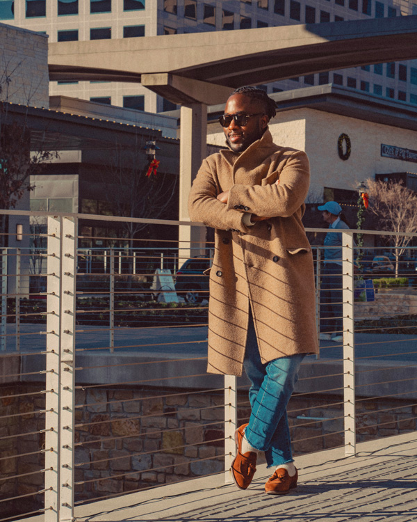man wearing camel coat with light wash jeans and suede loafers