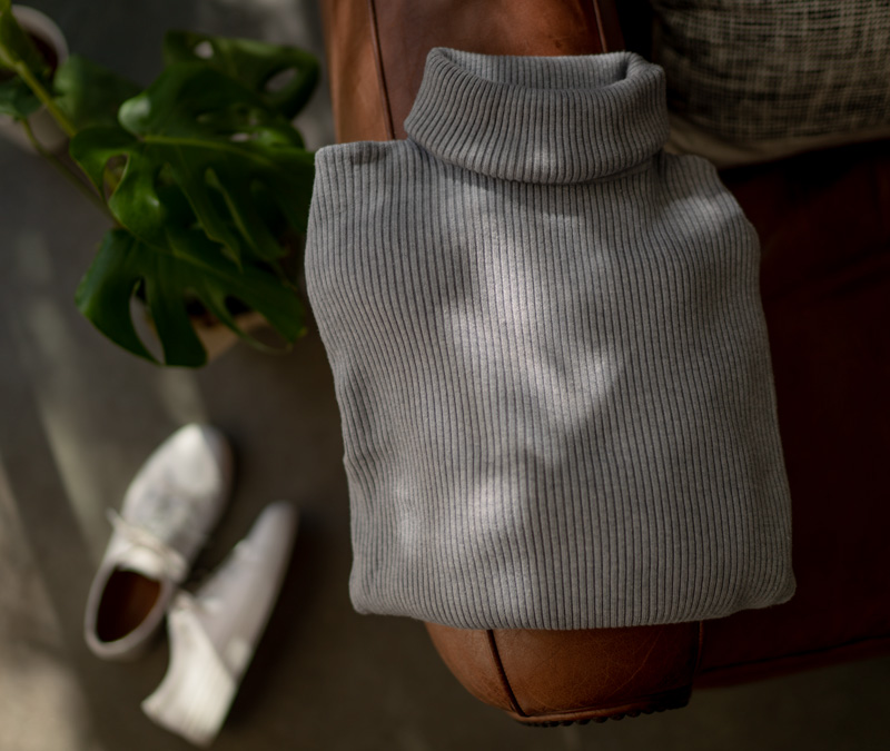 a turtleneck sweater sitting on a leather chair next to white sneakers