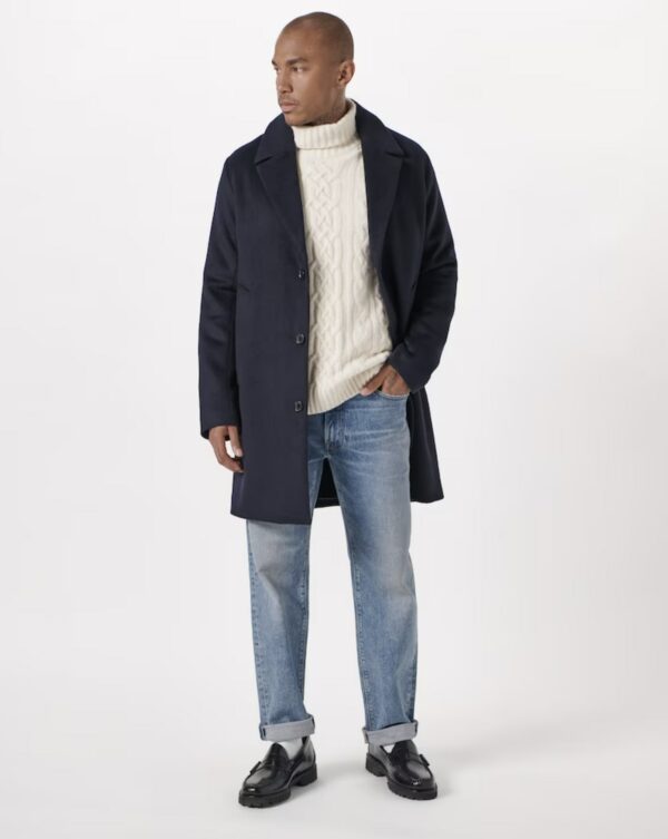 a man wearing a top coat and sweater and jeans