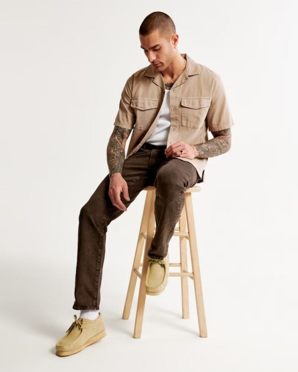 a man wearing a button front shirt and straight leg pants and clarks chukka style shoes