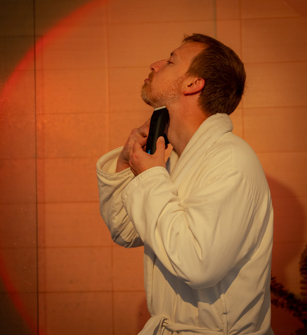 man using a brio beard trimmer wearing a bathrobe