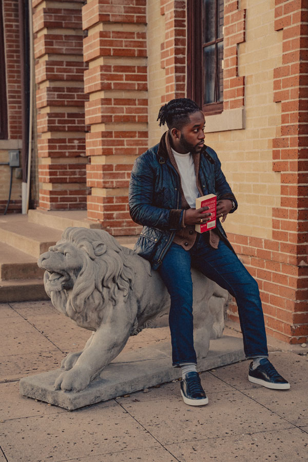 A casual spring outfit with a quilted jacket, shawl collar sweater, white t-shirt, blue jeans, and sneakers