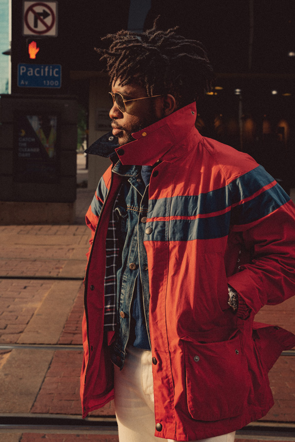 a man wearing a red raincoat over white denim jeans