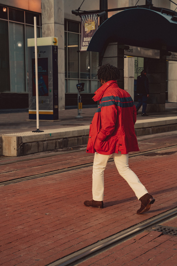 man wearing a red raincoat, white jeans, and jodhpur boots