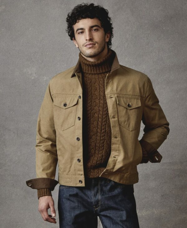 a man wearing a waxed jacket over a sweater