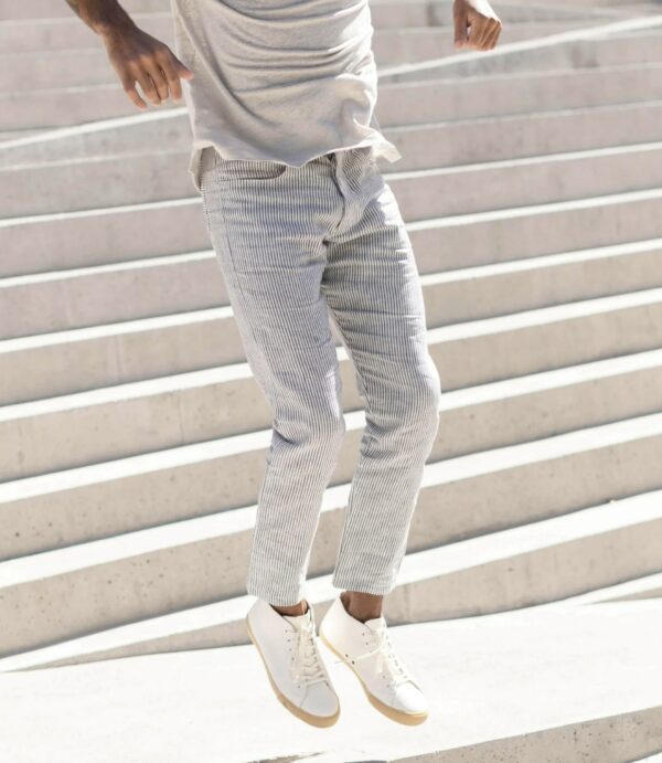 man in action shot jumping while wearing striped linen pants and gum sole shoes