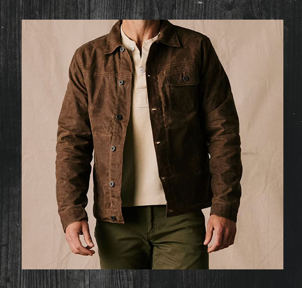 man wearing a waxed canvas jacket with a collared shirt and pants
