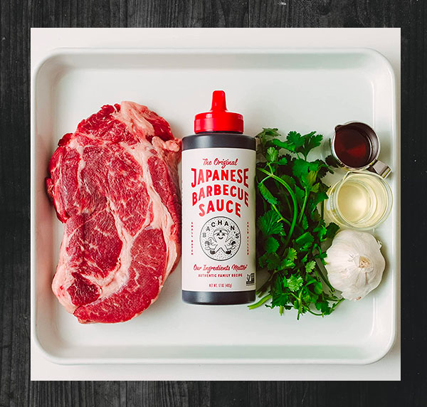 a tray of food containing steak and japanese style barbeque sauce and assorted vegetables and other ingredients