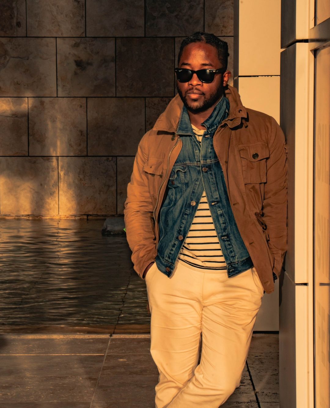 a man wearing khakhi pants with layered jackets and sunglasses