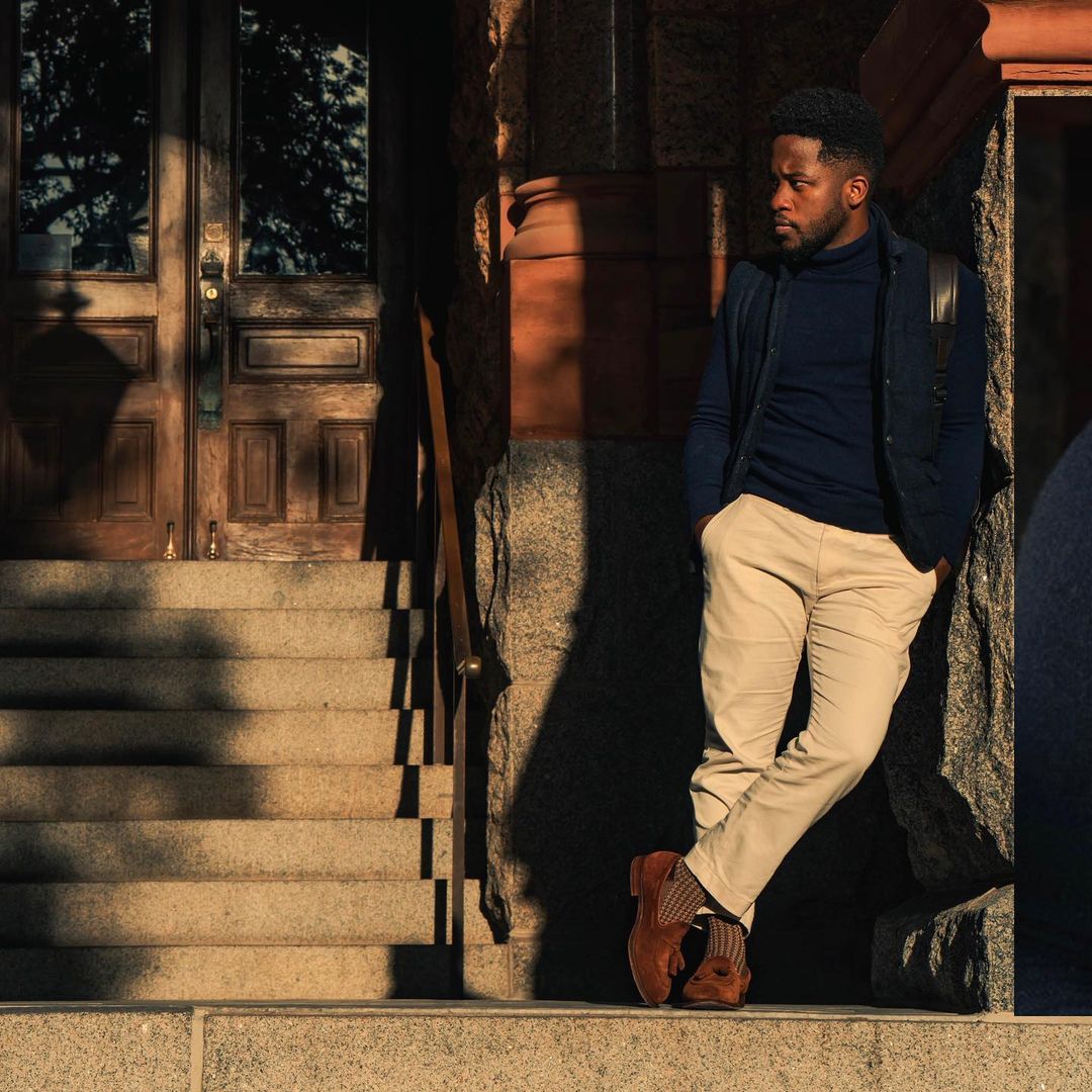 a man wearing khaki pants with a turtle neck and a jacket