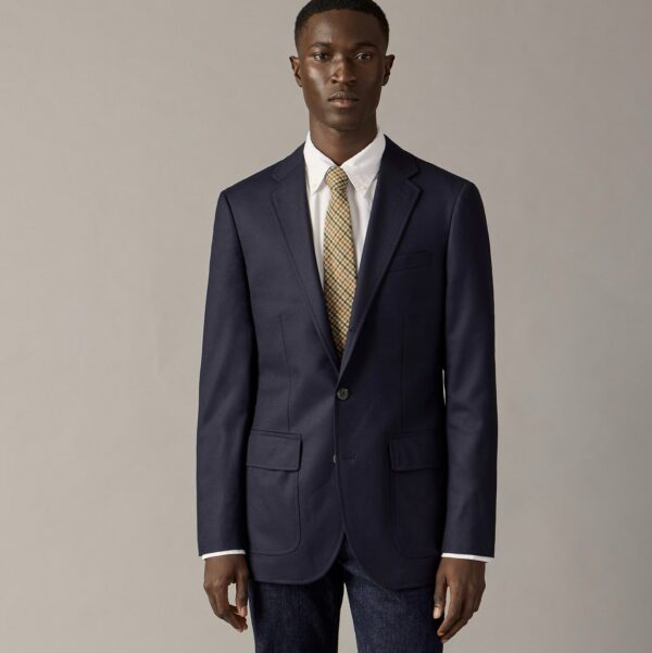 man wearing a blazer with a shirt and tie and denim jeans